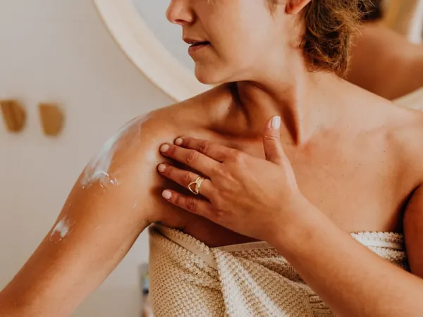 Woman applying body lotion during her care routine
