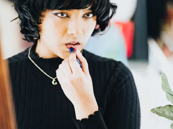Woman applying a bold lipstick in front of a mirror